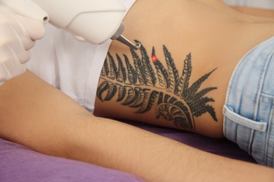 Young woman undergoing laser tattoo removal procedure in salon, closeup