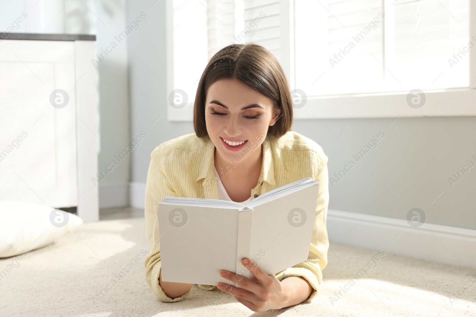 Photo of Beautiful young woman reading book at home