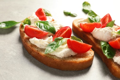 Photo of Toasted bread with tasty cream cheese and tomatoes on gray table