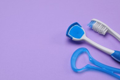 Photo of Tongue cleaners and toothbrush on violet background, above view. Space for text