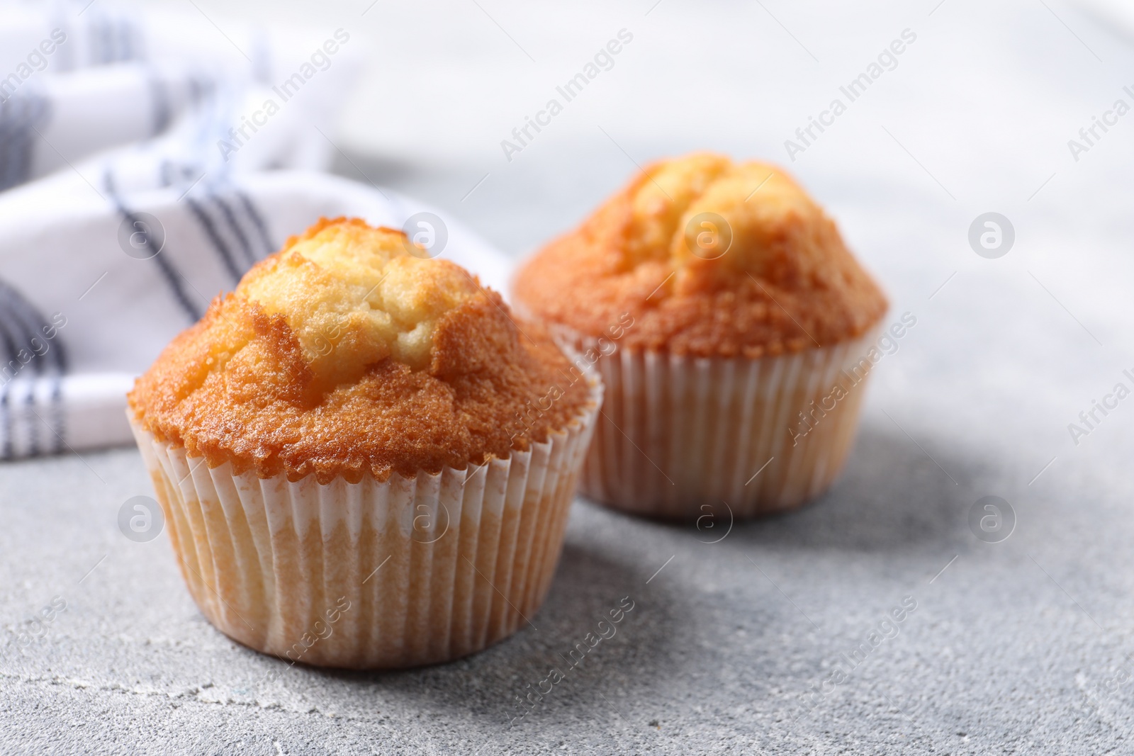 Photo of Delicious sweet muffins on light grey textured table, closeup. Space for text