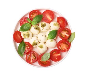 Photo of Plate of tasty Caprese salad with mozzarella, tomatoes, basil and pesto sauce isolated on white, top view