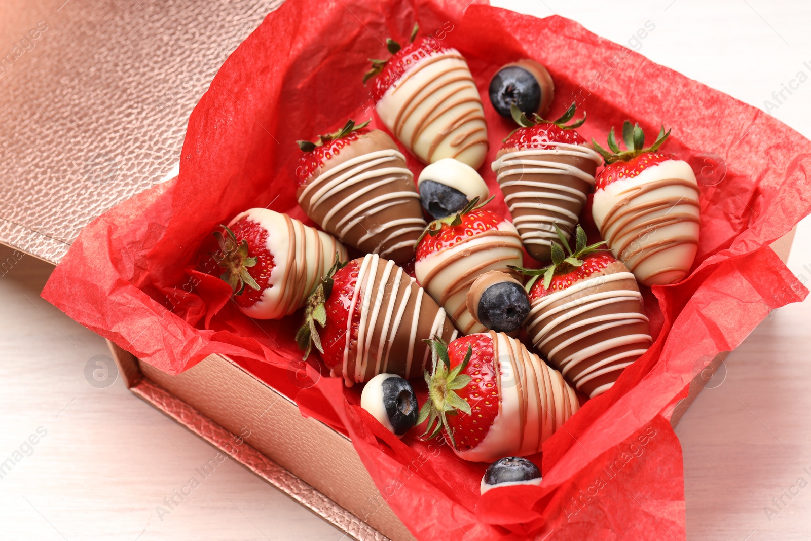 Photo of Box with delicious chocolate covered strawberries and blueberries on white table