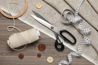 Flat lay composition with sewing accessories on wooden background