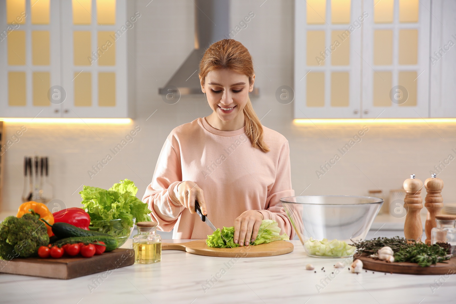 Photo of Young woman cooking at table in kitchen