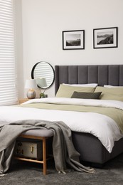 Window with horizontal blinds and comfortable bed in room