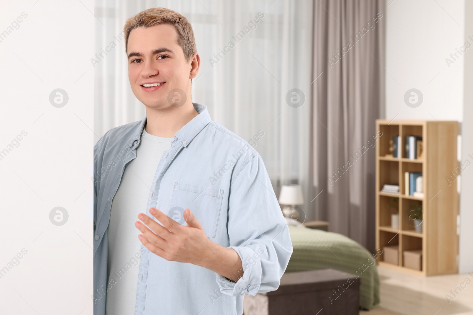 Photo of Happy man inviting to come in room