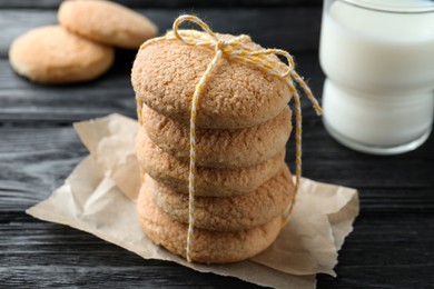 Photo of Delicious sugar cookies and glass of milk on black wooden table, closeup