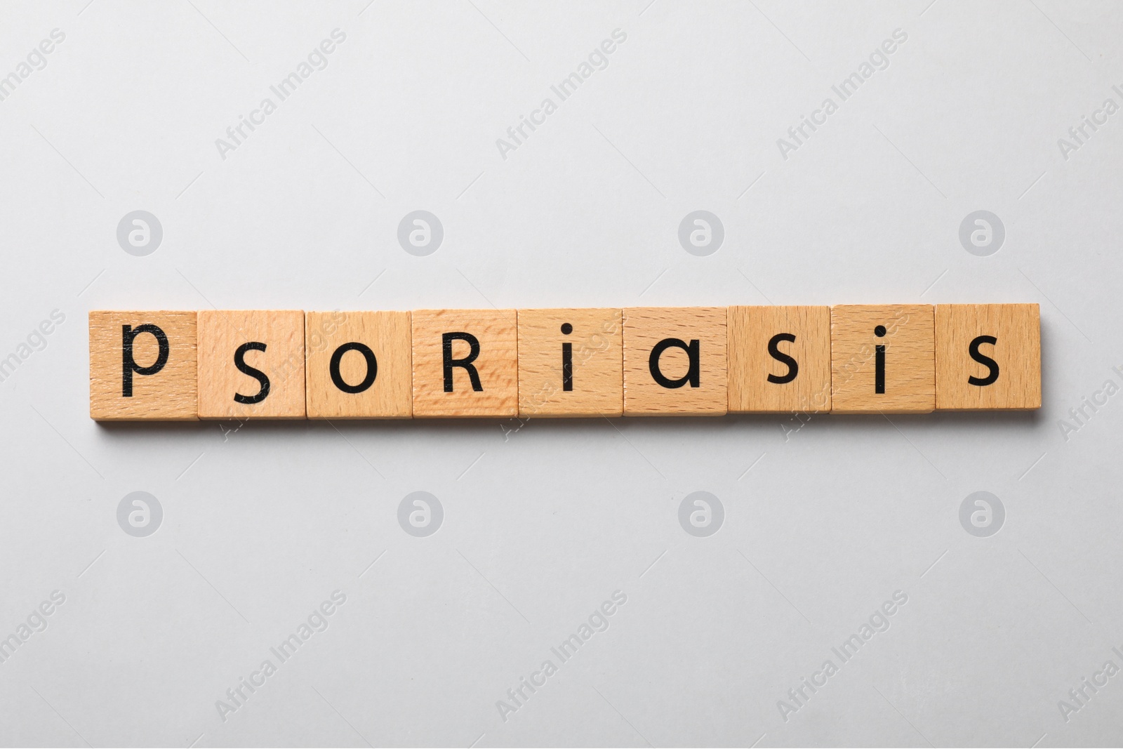 Photo of Word Psoriasis made of wooden squares with letters on light grey background, top view