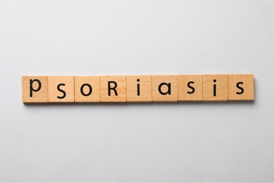Word Psoriasis made of wooden squares with letters on light grey background, top view
