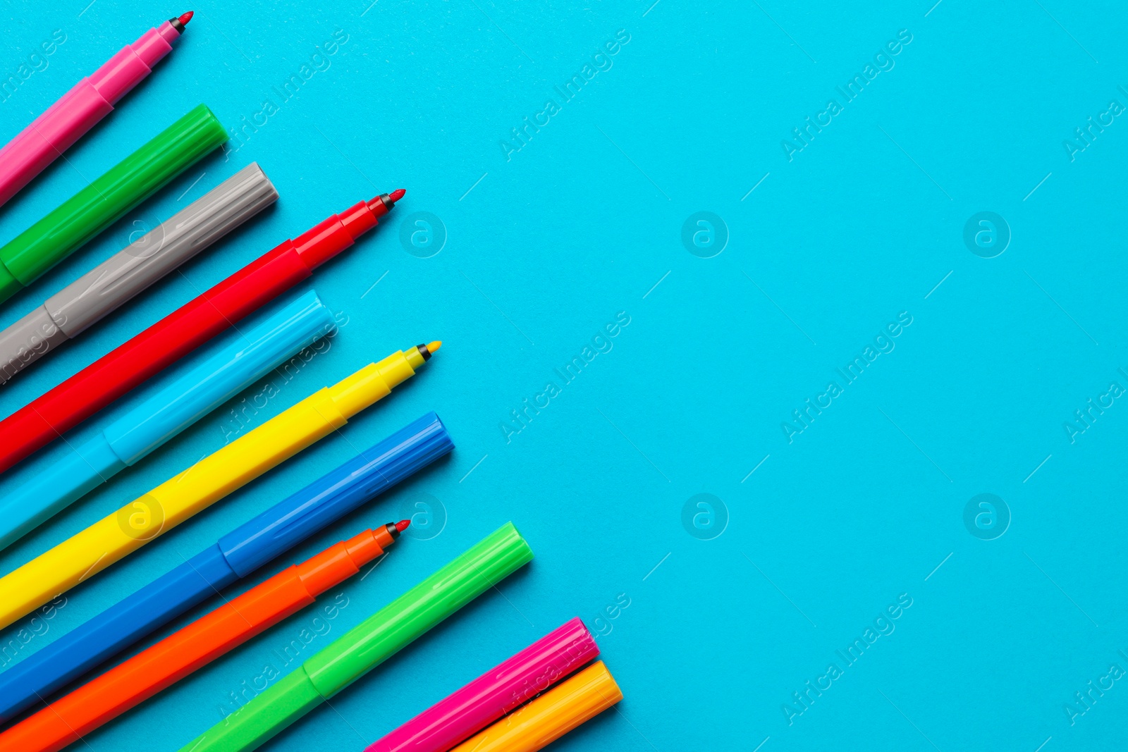 Photo of Many bright markers on light blue background, flat lay. Space for text