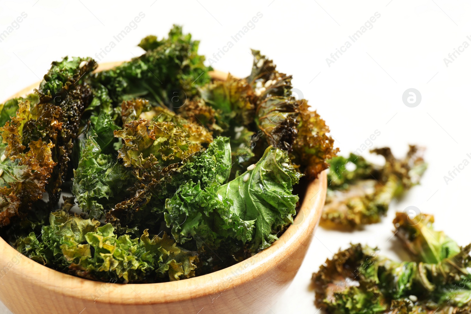 Photo of Tasty baked kale chips in wooden bowl, closeup