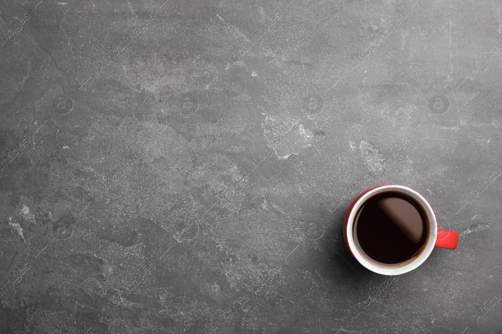 Photo of Ceramic cup with hot aromatic coffee on grunge background, top view