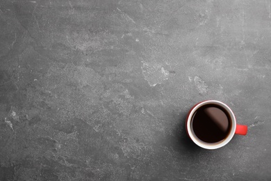 Ceramic cup with hot aromatic coffee on grunge background, top view