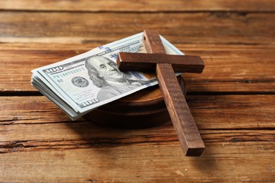 Cross and money on wooden table, closeup