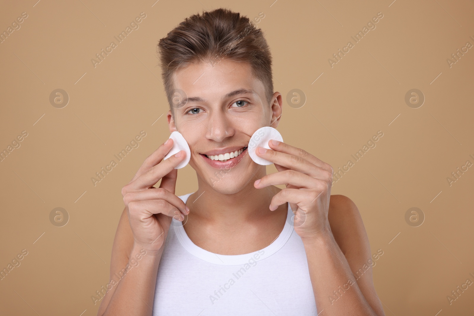 Photo of Handsome man with cotton pads on beige background