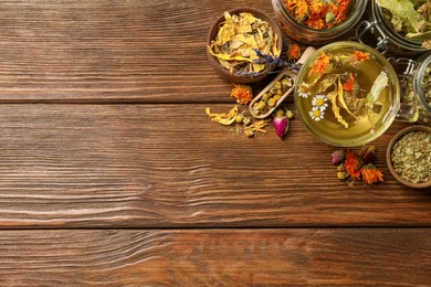 Photo of Freshly brewed tea and dried herbs on wooden table, flat lay. Space for text