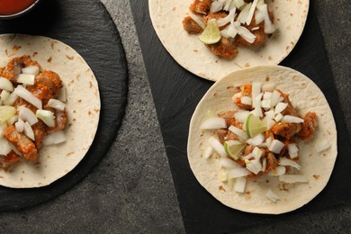 Delicious tacos with vegetables, meat and lime on grey textured table, flat lay