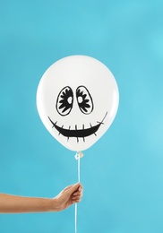 Photo of Woman holding spooky balloon for Halloween party on blue background