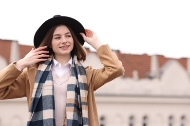 Photo of Beautiful woman in warm scarf and hat outdoors, space for text