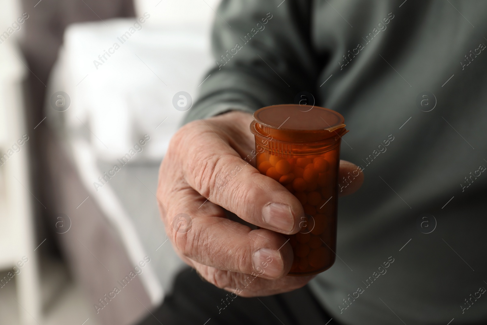 Photo of Senior man holding bottle with pills in his hand, closeup