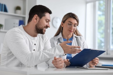 Professional doctor working with patient at white table in hospital