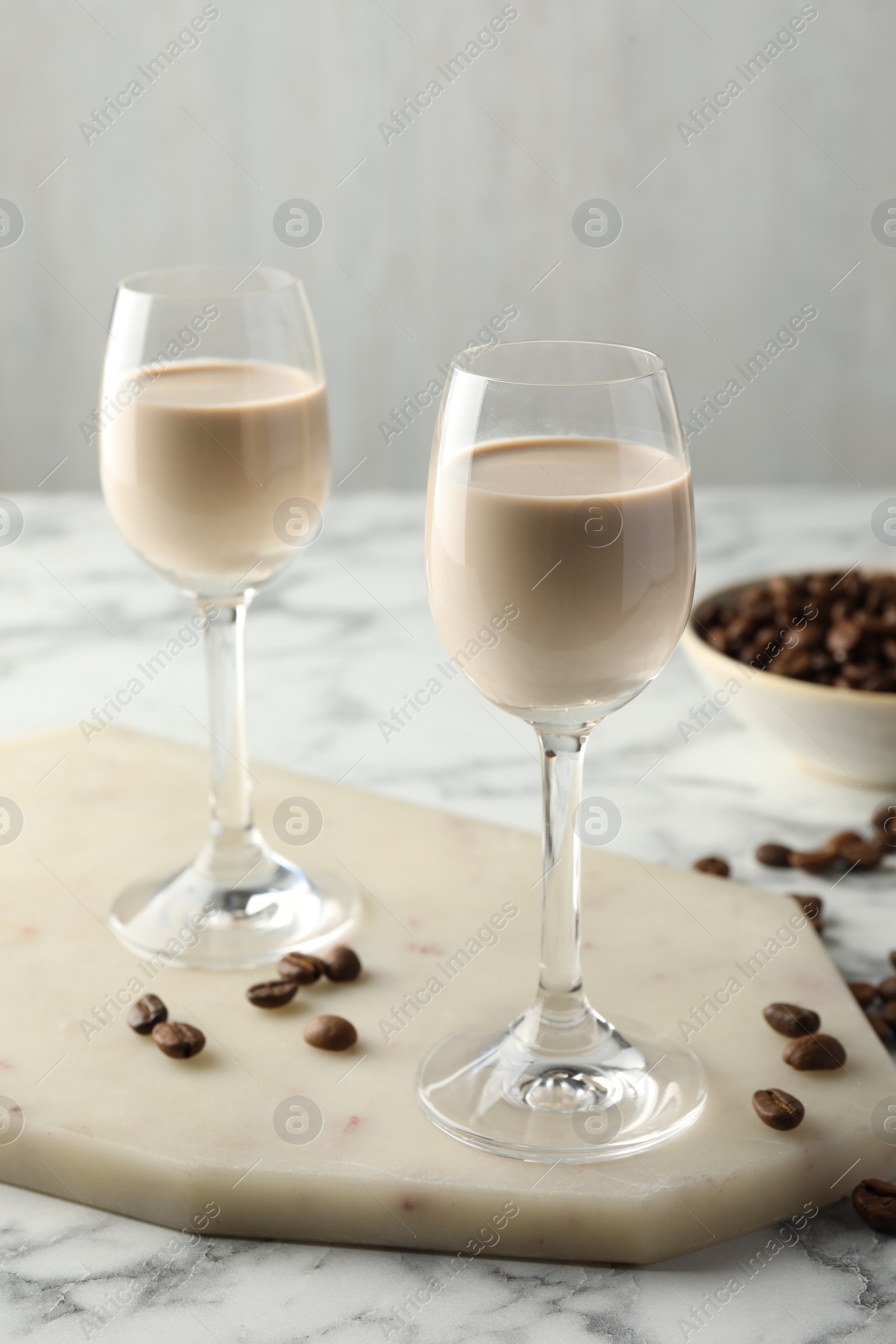 Photo of Coffee cream liqueur in glasses and beans on white marble table