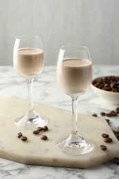 Photo of Coffee cream liqueur in glasses and beans on white marble table
