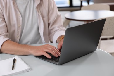 Man working on laptop at table in cafe, closeup