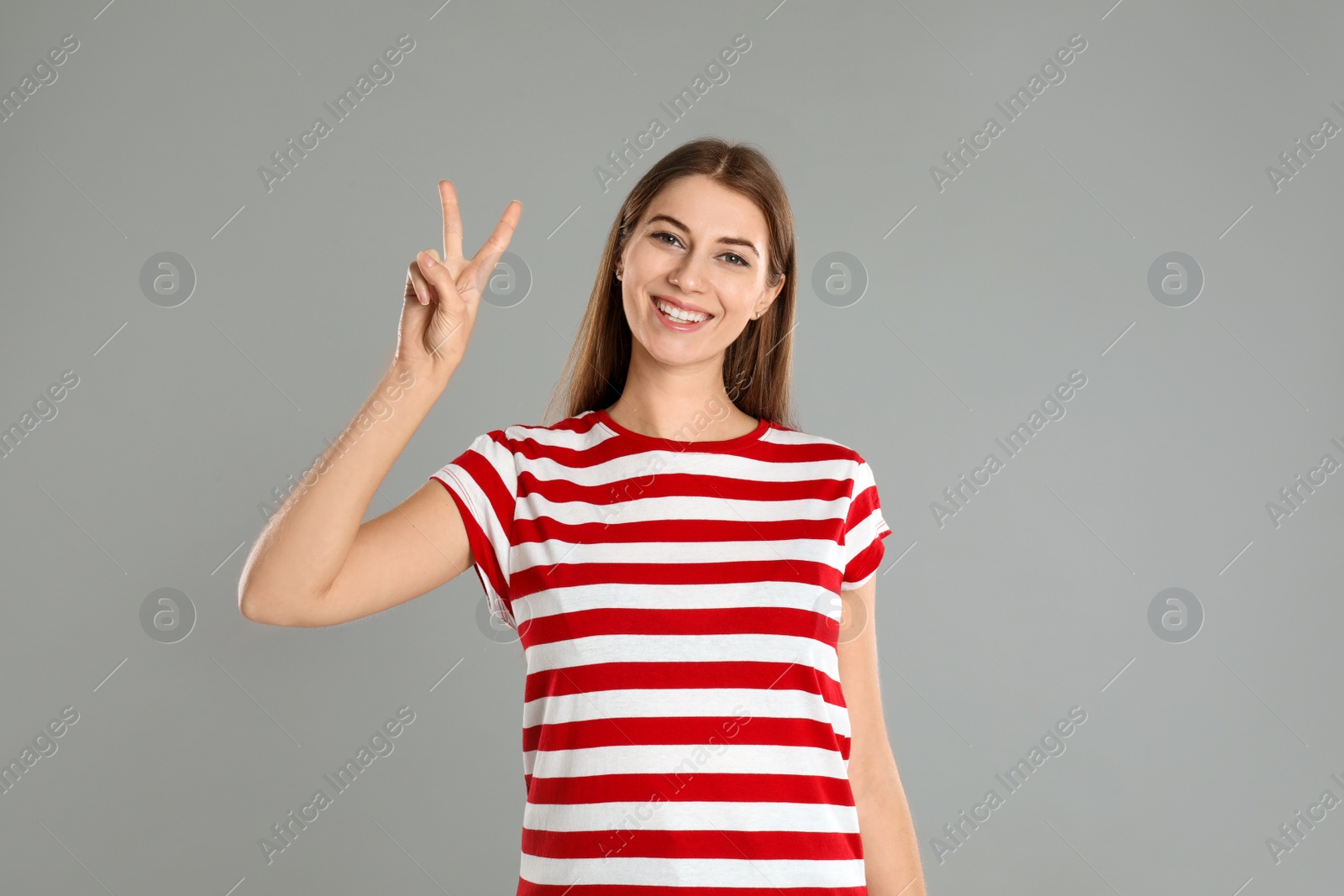 Photo of Woman showing number two with her hand on grey background