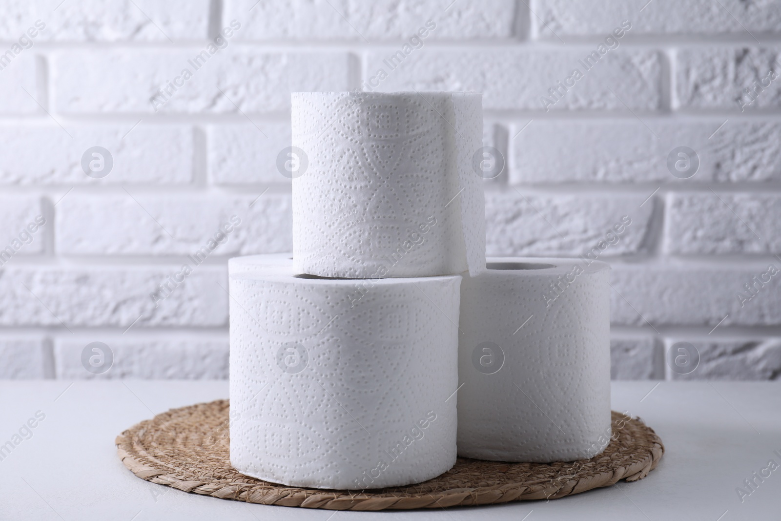 Photo of Toilet paper rolls on white table against brick wall