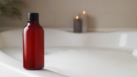 Photo of Red bottle of bubble bath on tub indoors, space for text