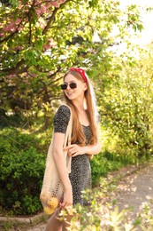 Beautiful teenage girl with apples in park on sunny day