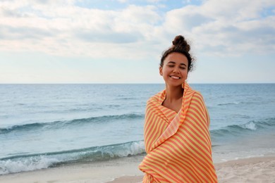 Photo of Beautiful African American woman with beach towel on seashore