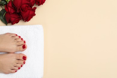 Photo of Woman with stylish red toenails after pedicure procedure and rose flowers on beige background, top view. Space for text