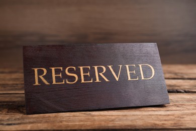 Elegant sign RESERVED on wooden surface. Table setting element