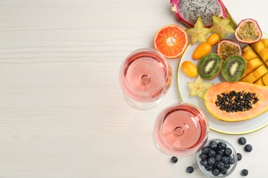Photo of Delicious exotic fruits and wine on white wooden table, flat lay. Space for text