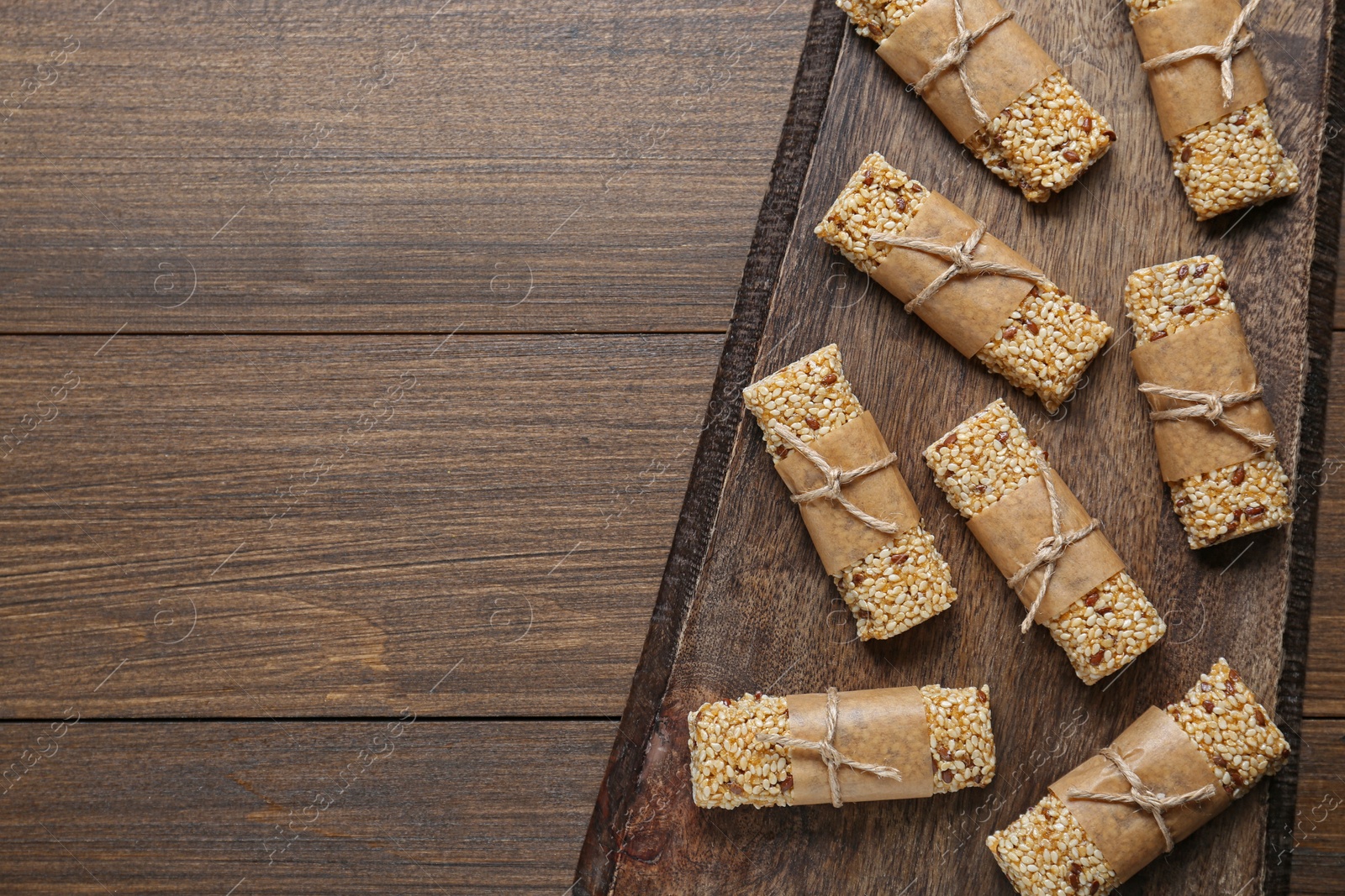 Photo of Tasty sesame seed bars on wooden table, top view. Space for text