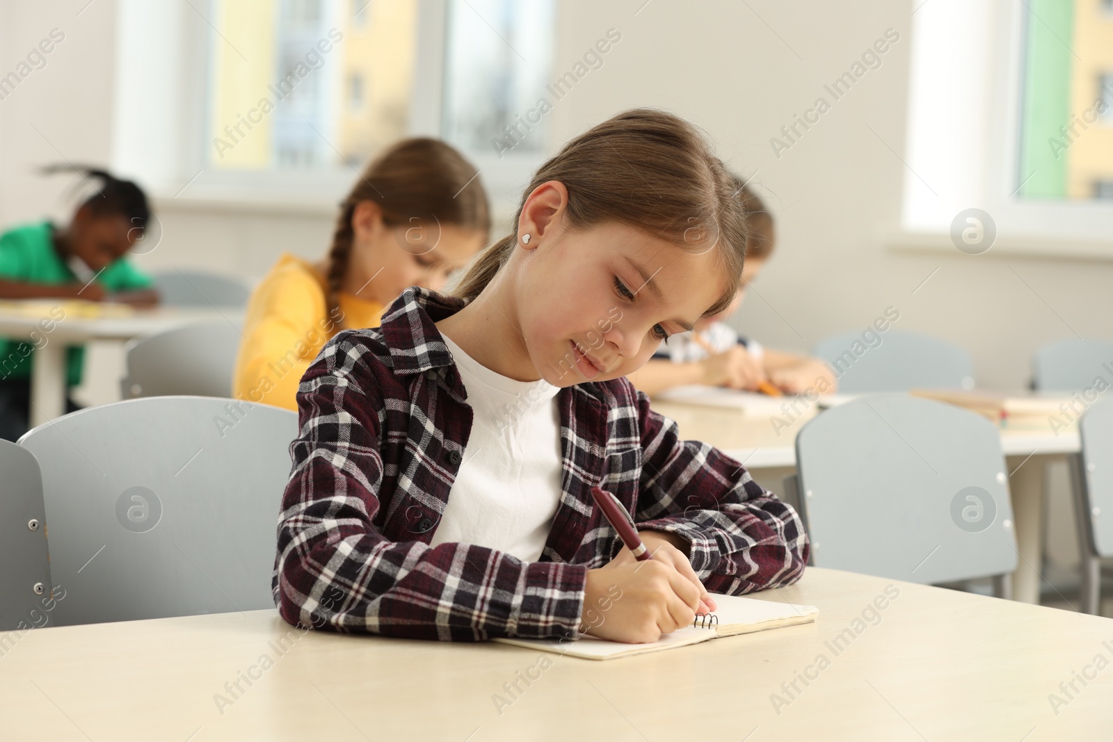 Photo of Cute little girl studying in classroom at school