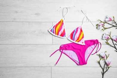 Photo of Flat lay composition with bikini and flowers on wooden background