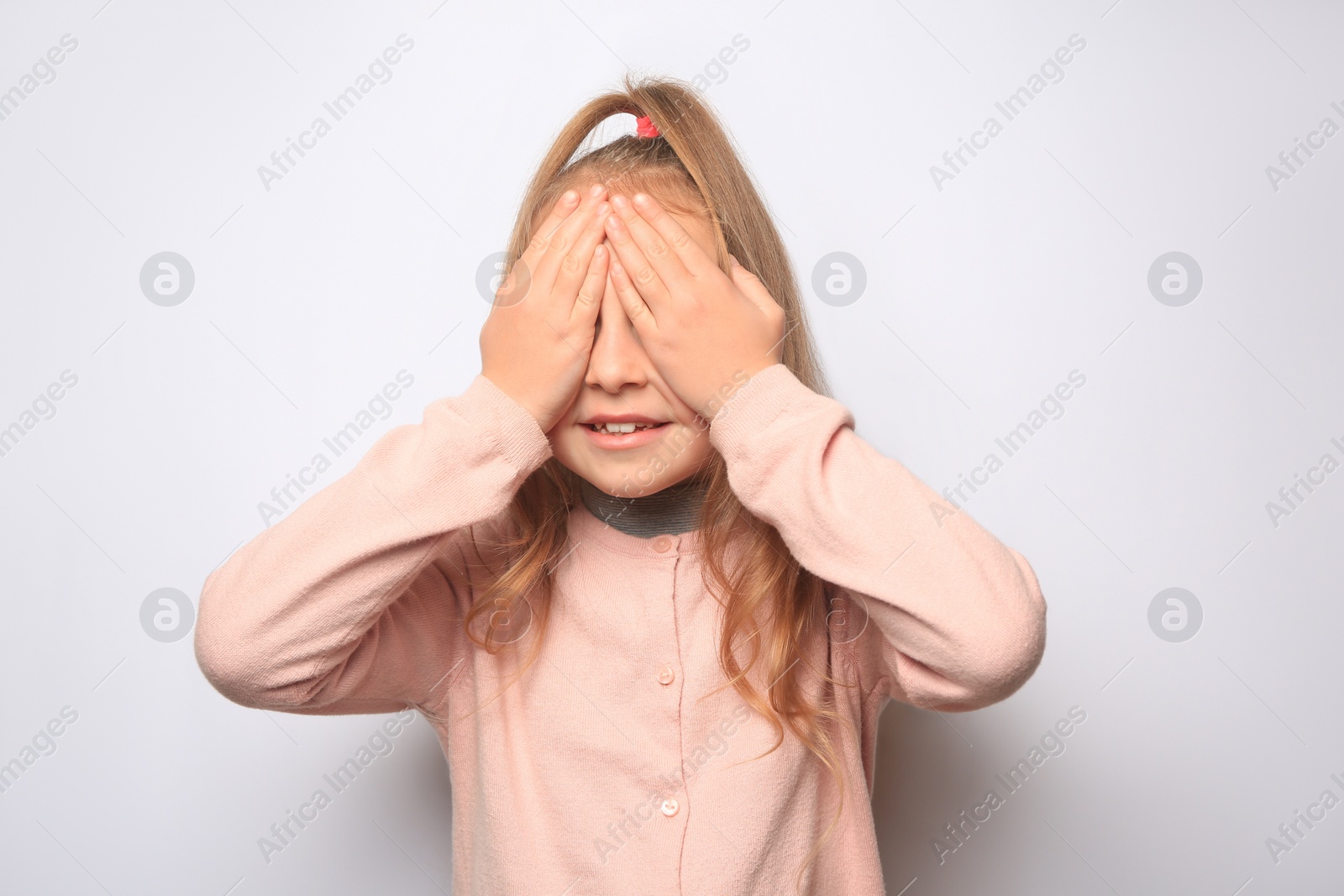 Photo of Happy little girl closing her eyes with hands on white background