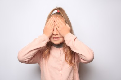 Happy little girl closing her eyes with hands on white background