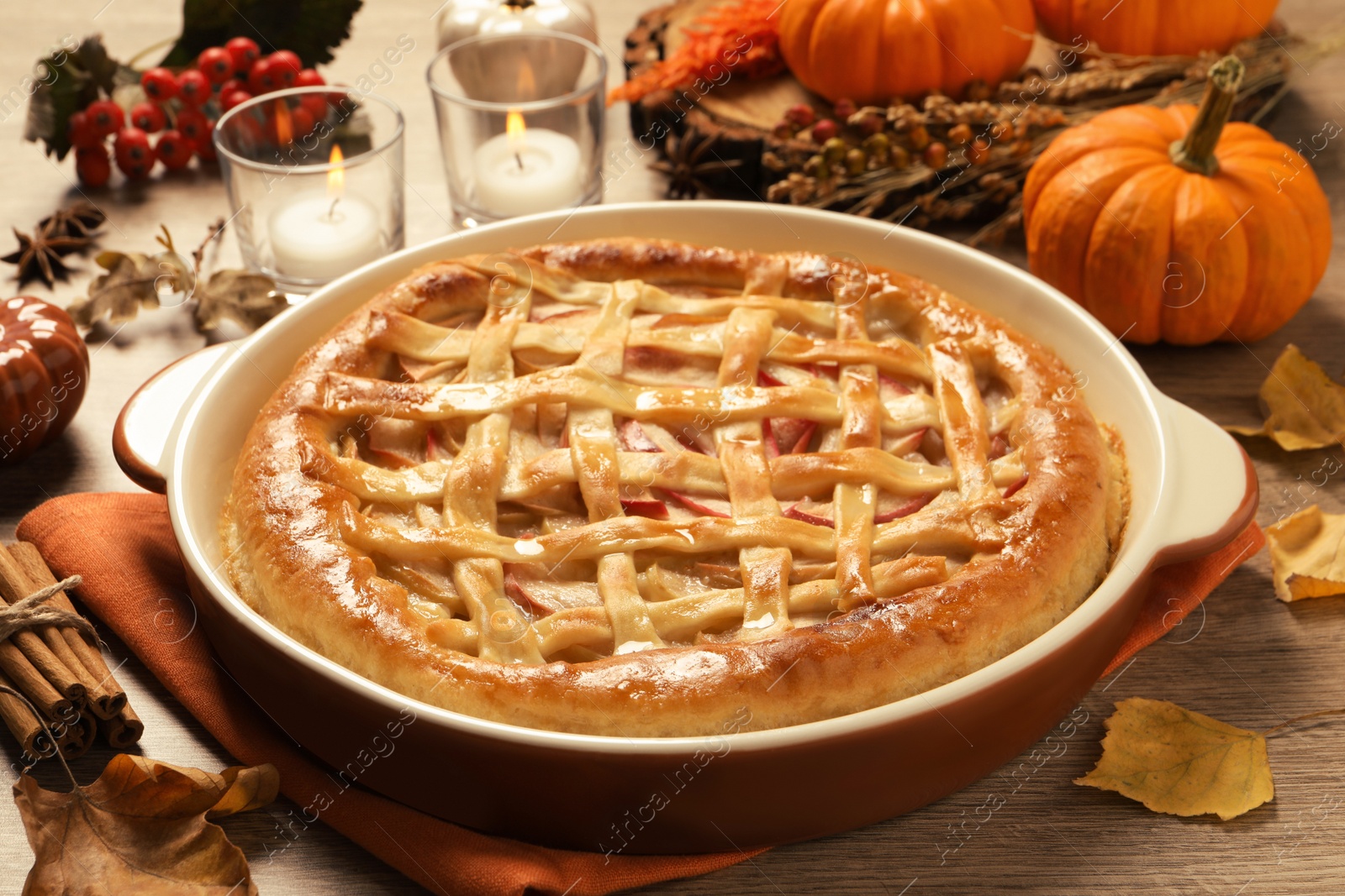 Photo of Delicious homemade apple pie and autumn leaves on wooden table. Thanksgiving Day celebration