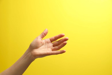 Photo of Woman holding something in hand on yellow background, closeup. Space for text