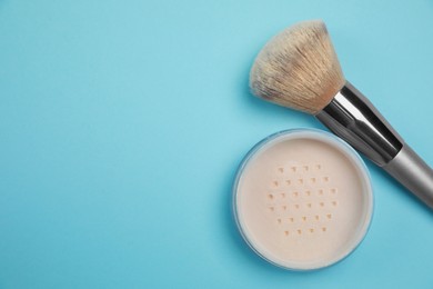 Photo of Loose face powder and brush on light blue background, flat lay. Space for text