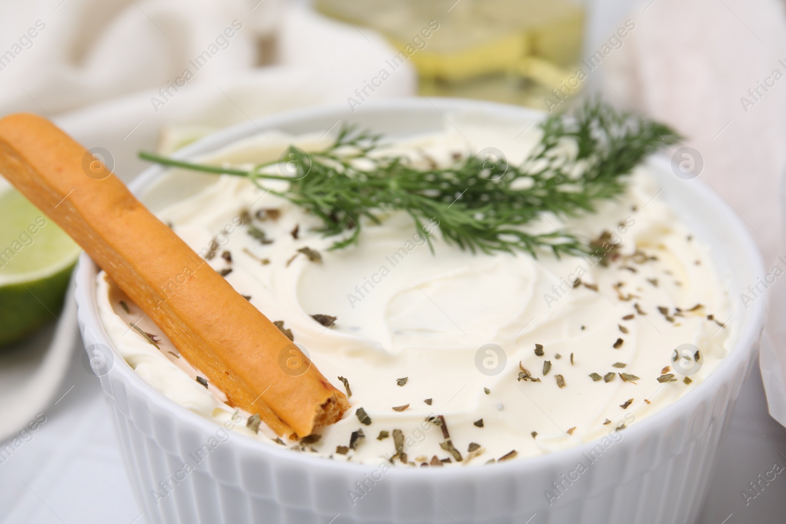 Photo of Delicious cream cheese with grissini stick and dill on white table, closeup