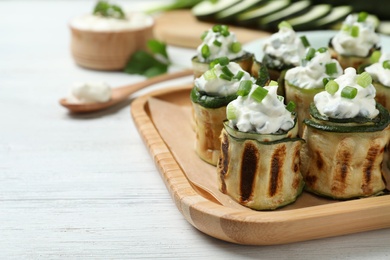 Photo of Tasty stuffed zucchini rolls on white wooden table, closeup. Space for text