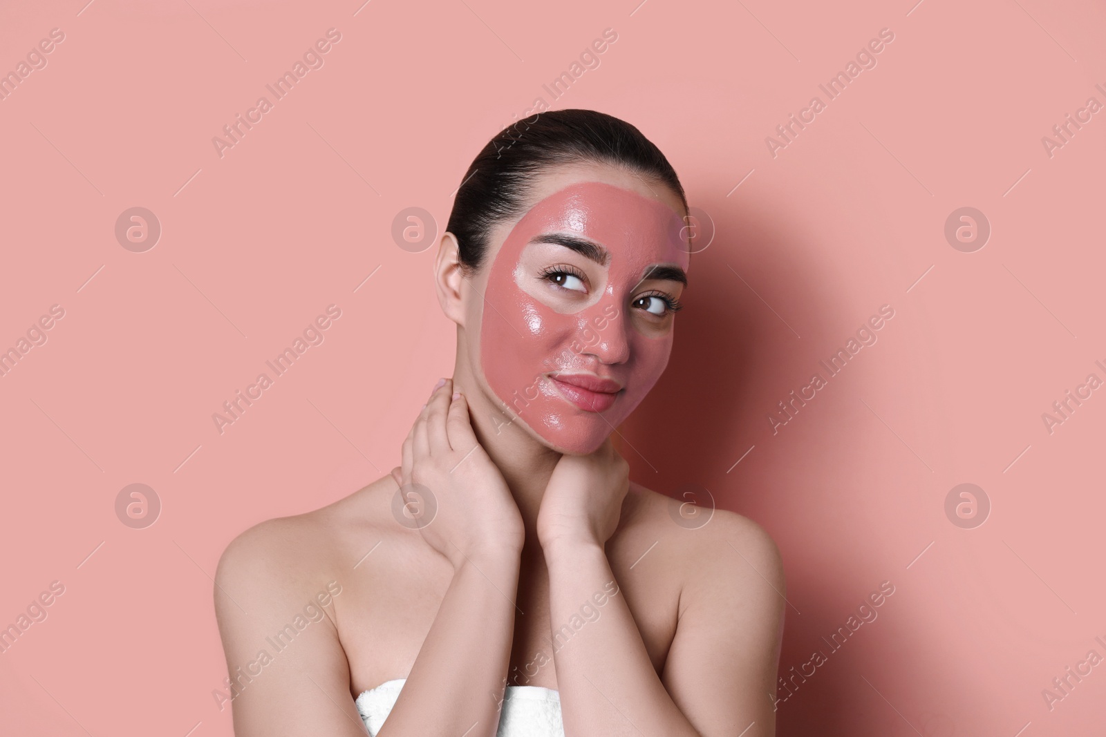 Photo of Woman with pomegranate face mask on pale coral background