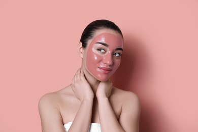 Photo of Woman with pomegranate face mask on pale coral background