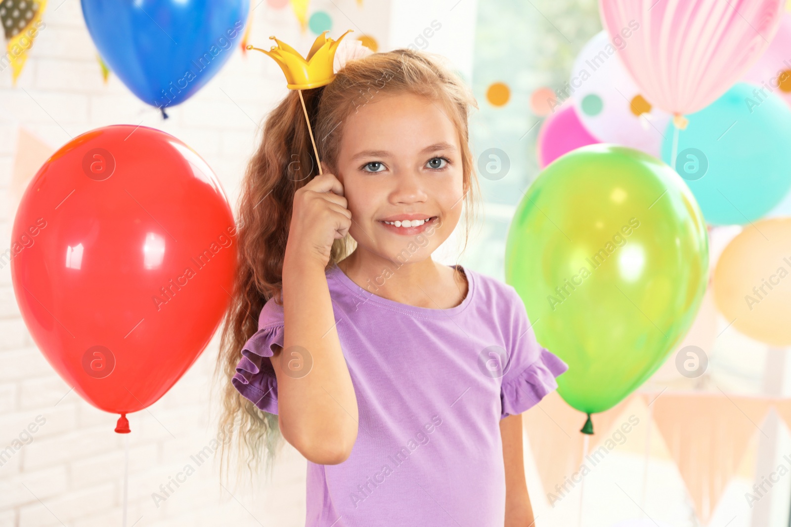 Photo of Happy girl near bright balloons at birthday party indoors